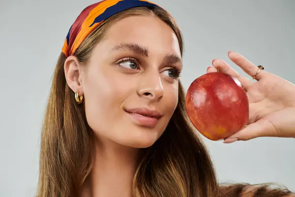 Young woman showcases her summer style while holding a bright apple in a studio. — Stock Photo