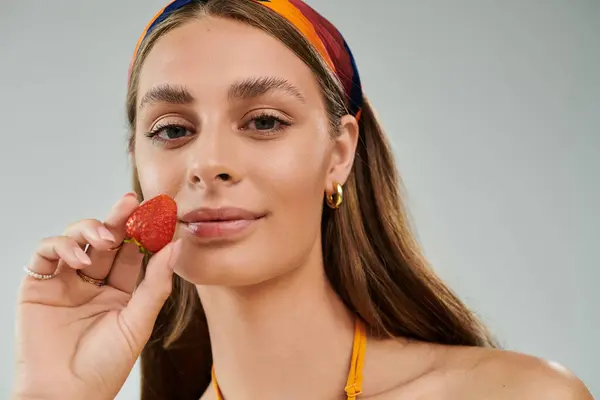 A young woman in a vibrant summer outfit poses with a strawberry, showcasing her natural beauty. — Stock Photo