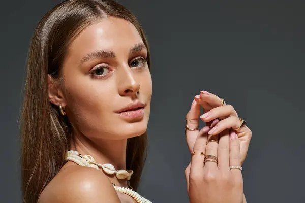 Young woman with tan skin poses in a chic summer outfit, showcasing her seashell necklace. — Stock Photo
