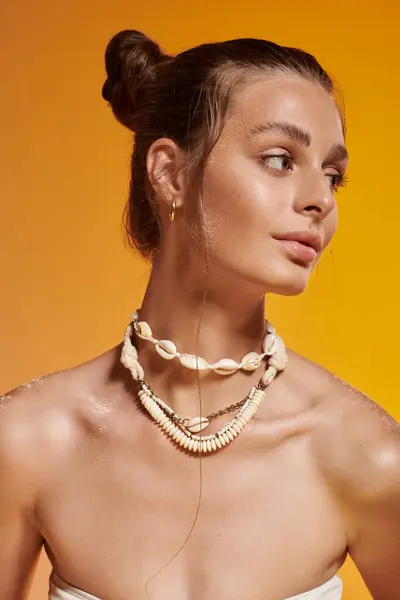 A young woman poses in a stylish summer outfit with seashell jewelry in a studio. — Stock Photo