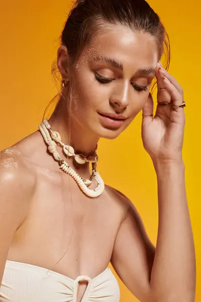 A young woman poses gracefully in her summer outfit, showcasing a beautiful seashell necklace. — Stock Photo