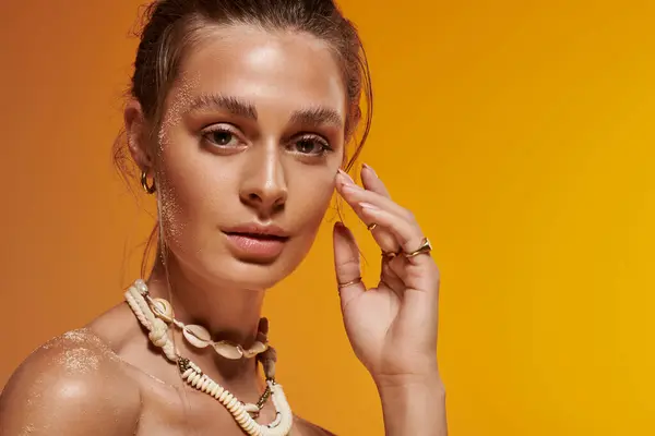 A young woman showcases a summer outfit and seashell necklace in a studio. — Stock Photo