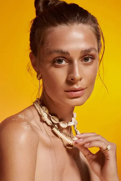 Young woman with tan skin and natural makeup poses in a summer outfit with seashell accessories. — Stock Photo