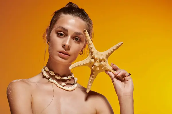 Young woman showcases summer fashion with a seashell necklace and natural glow in a studio. — Stock Photo