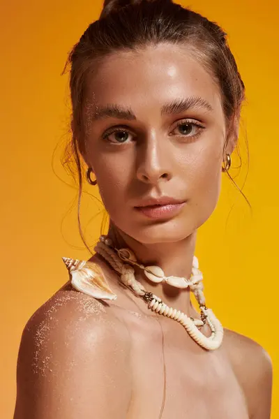 A stunning young woman models her summer look with a seashell necklace in a vibrant studio. — Stock Photo
