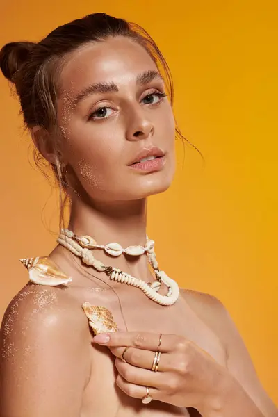 Young woman shows summer style with a seashell necklace and natural makeup under studio lights. — Stock Photo