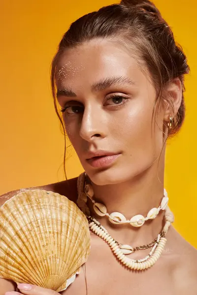 A young woman shines in summer style with a seashell necklace in a vibrant studio. — Stock Photo