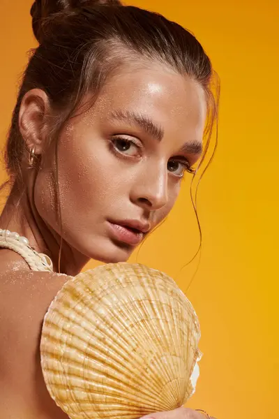 Young woman with tan skin poses gracefully in summer day with a seashell. — Stock Photo