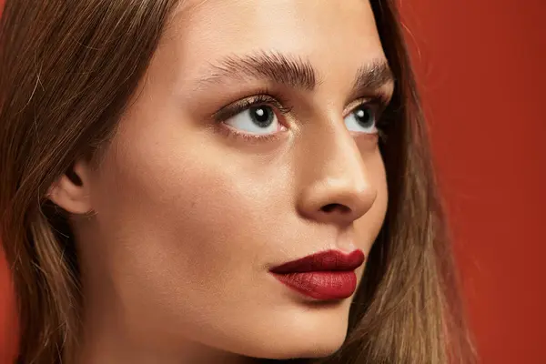 A young beautiful woman gazes thoughtfully with captivating makeup and a vivid background. — Stock Photo