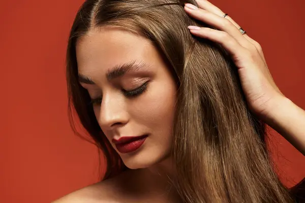 Beautiful young woman with long hair gently touching her hair, enjoying a moment of tranquility. — Stock Photo