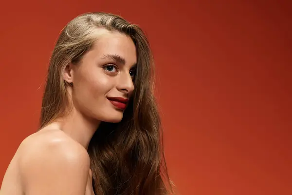 A stunning woman poses gracefully, her long hair and radiant smile dazzling against a bold backdrop. — Stock Photo