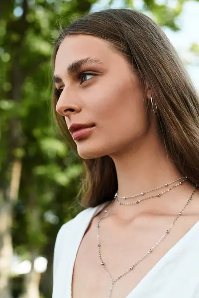 A beautiful young woman stands gracefully, adorned in stunning jewelry, immersed in natures beauty. — Stock Photo