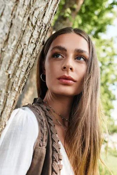 Bright sunlight highlights the features of a thoughtful young woman leaning against a tree trunk. — Stock Photo