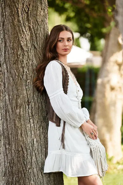 A young beautiful woman stands gracefully against a tree, enjoying a peaceful afternoon moment. — Stock Photo