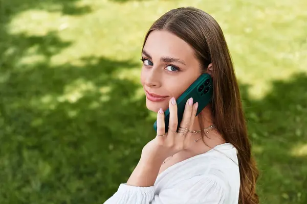 Beautiful woman engages in a cheerful conversation on the phone amidst vibrant greenery. — Stock Photo