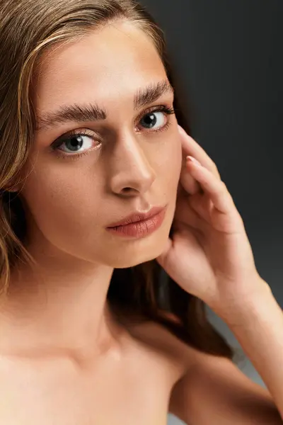 A young beautiful woman softly rests her hand on her cheek while gazing into the distance. — Stock Photo