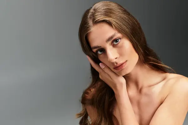 A striking young woman rests her hand on her cheek, showcasing her natural beauty and elegance. — Stock Photo