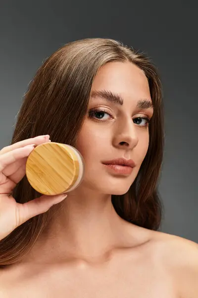Young beautiful woman highlights skincare product, emphasizing her radiant and glowing complexion. — Stock Photo