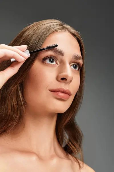 Young beautiful woman focuses intently while styling her eyebrows with a brush for a flawless look — Stock Photo
