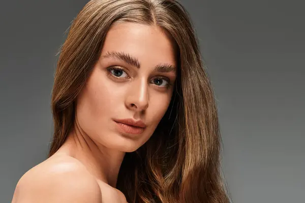 Elegant young woman poses, highlighting her flawless skin and expressive gaze in soft light. — Stock Photo