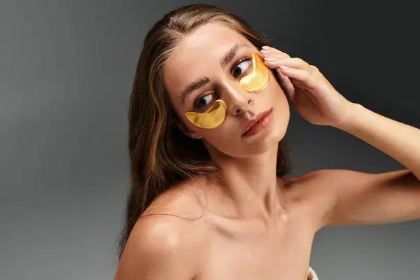 Young woman applies luxurious eye patches, embodying relaxation and self care in a calm environment. — Stock Photo