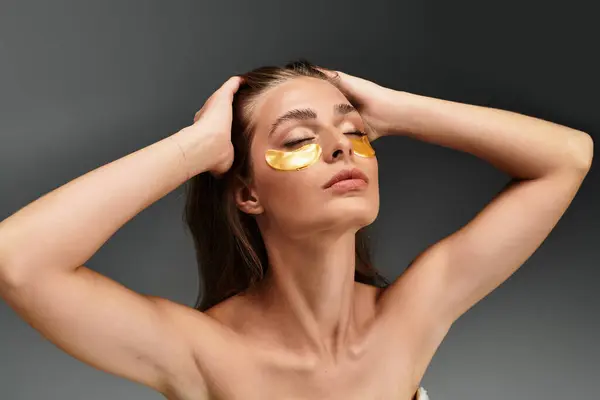 A young woman relaxes with gold eye masks, enhancing her beauty in a serene setting. — Stock Photo