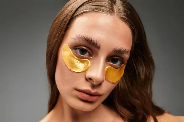 Young woman applies eye masks, embracing relaxation and skincare in a tranquil setting. — Stock Photo