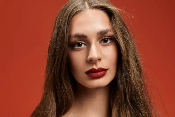 A young beautiful woman poses thoughtfully with long hair and bold lips, radiating confidence. — Stock Photo