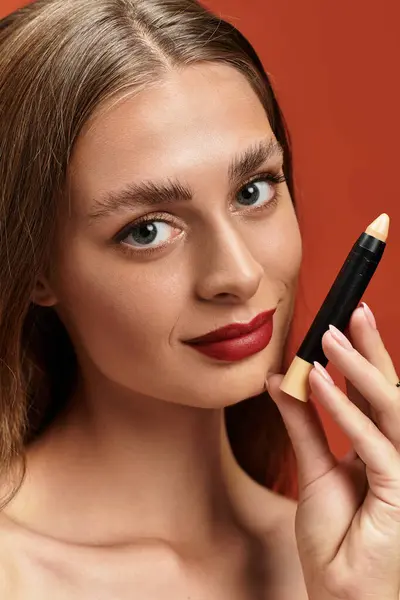 Young woman shows off her makeup skills, smiling against a vibrant backdrop. — Stock Photo