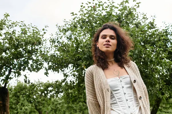 Young woman in a stylish outfit stands gracefully in a green park on a sunny summer day. — Stock Photo