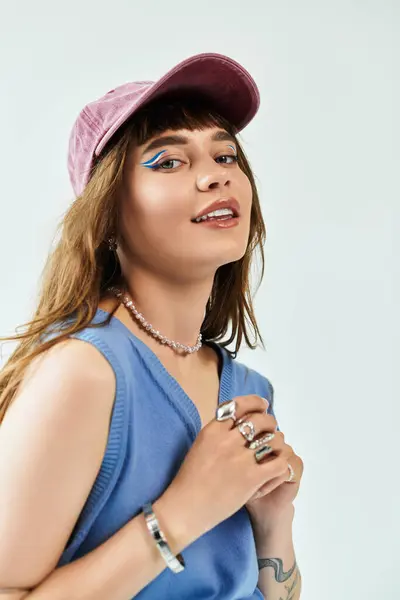 Una giovane donna elegante posa con un berretto alla moda, trucco vibrante e gioielli chic. — Foto stock