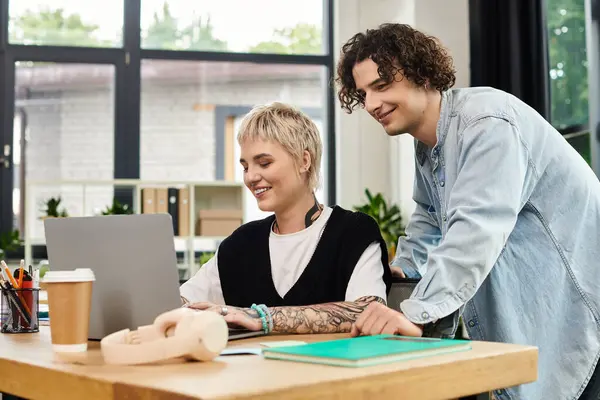 Two enthusiastic young individuals focus on a laptop in a bright, contemporary office setting. — Stock Photo