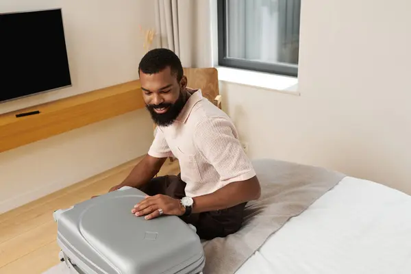 Elegante hombre desempaca su equipaje en una elegante habitación de hotel, listo para su aventura de viaje. - foto de stock