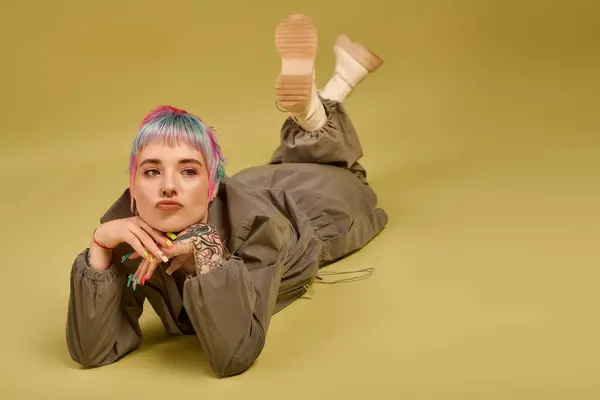 Una giovane donna creativa si rilassa sul pavimento dello studio, ostentando i suoi capelli colorati e lo stile unico. — Foto stock