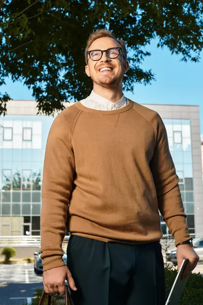 Giovane insegnante di sesso maschile si trova con fiducia all'aperto, sorridendo brillantemente su uno sfondo vibrante. — Foto stock