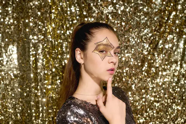 Una ragazza con una stella dipinta sul viso posa fiduciosa in mezzo a paillettes d'oro per Halloween. — Stock Photo