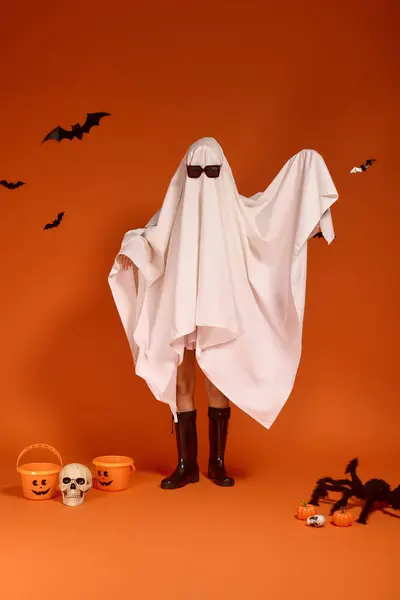 Веселая девушка в костюме призрака наслаждается празднованием Хэллоуина на оранжевом фоне. — стоковое фото