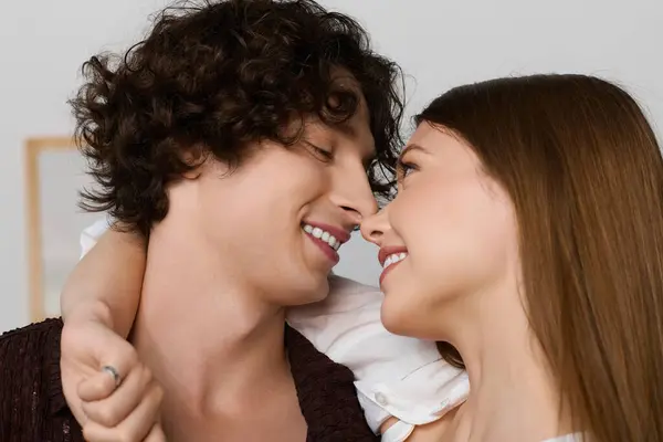 A curly-haired man and beautiful woman share smiles in their modern apartment filled with joy. — Stockfoto