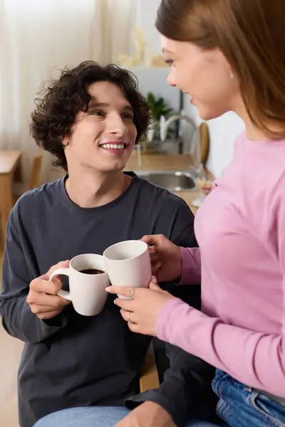 A joyful couple enjoys coffee in their stylish apartment, smiling and creating memories together. — Stockfoto