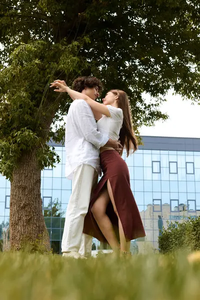 A happy young couple embraces in a lush green area, enjoying their time together outdoors. — Photo de stock