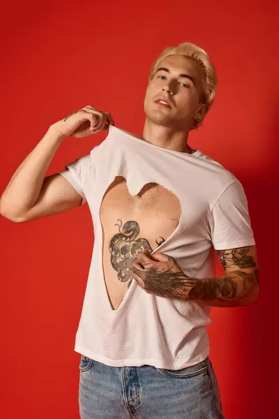 Handsome young man expresses creativity in trendy attire while standing against a bold red wall. — Stock Photo