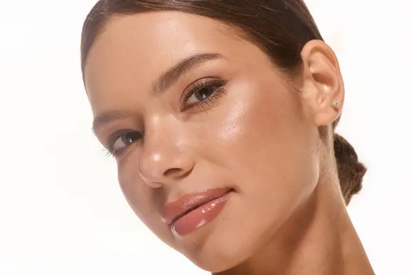 A beautiful young woman poses gracefully with natural makeup against a clean white backdrop. — Stock Photo