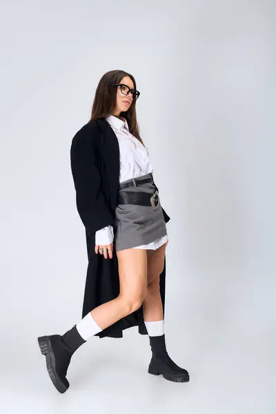 A beautiful young woman poses confidently in a trendy autumn outfit with a white shirt and skirt. — Stock Photo