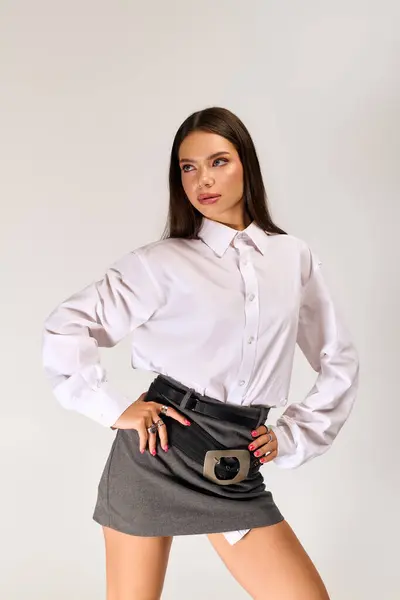 Beautiful young woman poses confidently in a trendy autumn outfit featuring a white shirt and skirt. — Stock Photo