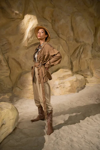 サファリハットとベージュの服の考古学者の完全な長さは洞窟の中で手で立っている — ストック写真