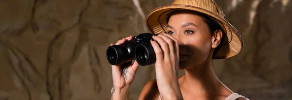 Young Pretty Archaeologist Safari Hat Holding Binoculars Looking Away Cave — Stock Photo, Image