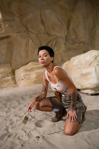 Tattooed Archaeologist Tank Top Shorts Holding Brush Sand Desert — Stock Photo, Image