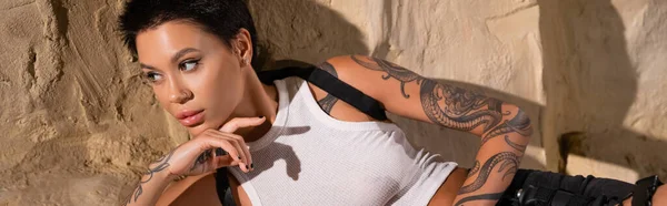 Sexy Tetovaný Archeolog Bílém Tričku Ležící Poblíž Skály Dívající Jinam — Stock fotografie
