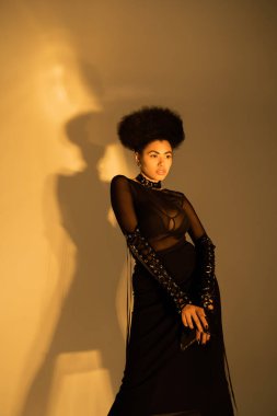 Seksi şeffaf gömlekli ve sarı sütyenli kıvırcık Afrikalı Amerikan modeli. 
