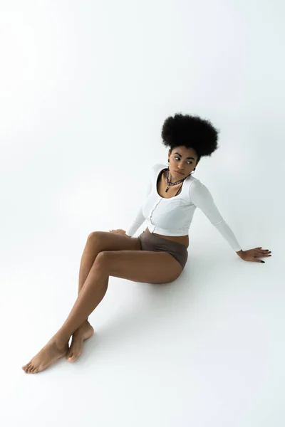 長い袖のシャツを着た若いアフリカ系アメリカ人女性の高い角度の眺めと白に座っているパンティー — ストック写真